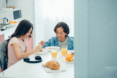 Two friendly kids having tasty meal together at home