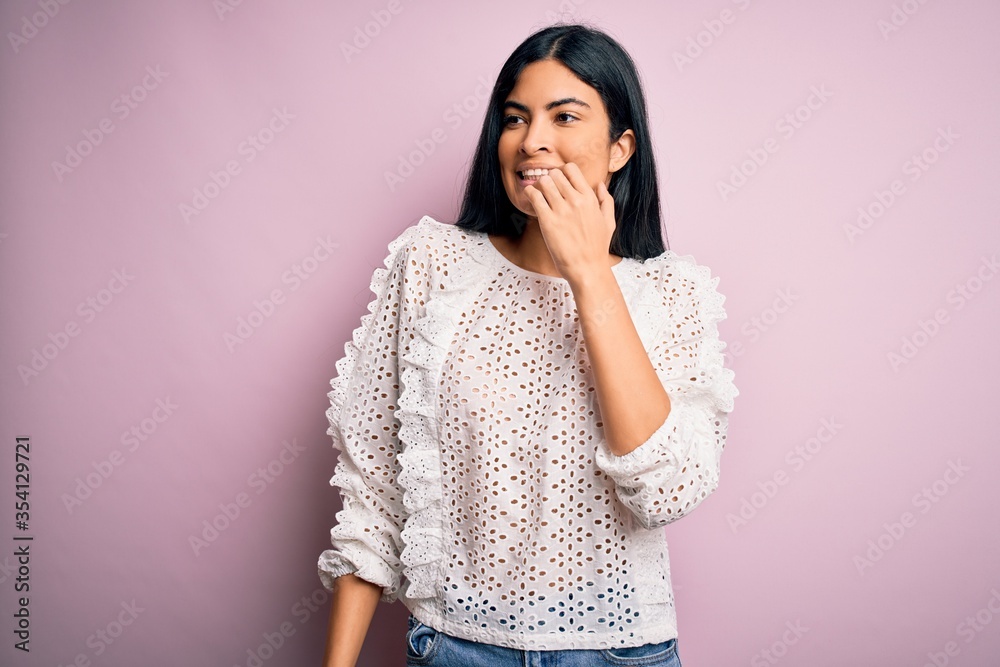 Young beautiful hispanic fashion woman wearing elegant shirt over pink background looking stressed and nervous with hands on mouth biting nails. Anxiety problem. Young beautiful hispanic fashion woman wearing elegant shirt over pink background looking stressed and nervous with hands on mouth biting nails. Anxiety problem.