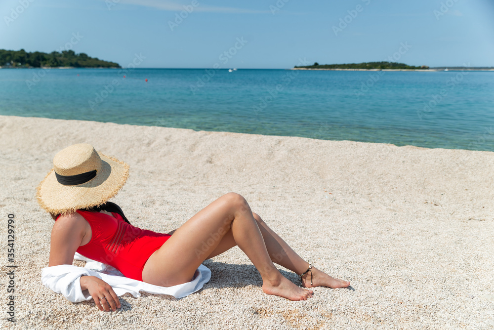 sexy women in red swimsuit laying at sunny sea beach