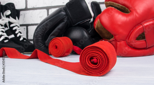 bandages for fixing joints, sneakers, a red protective helmet and boxing gloves, against a light brick wall, close-up