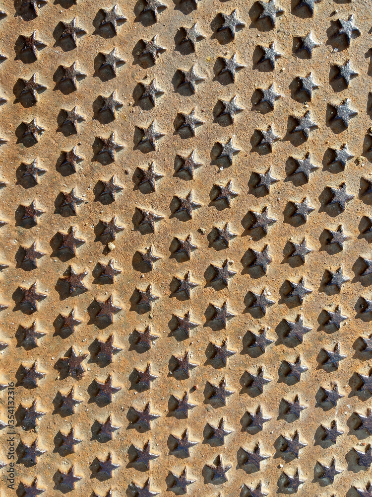 Metal background. View of a rusty metal plate with numerous small stars Metal background. View of a rusty metal plate with numerous small stars