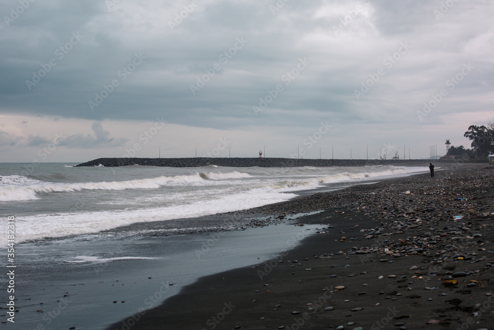 Splashing waves and cloudy sky on a pebble beach in Batumi. Autonomous Republic of Adjara, Georgia.