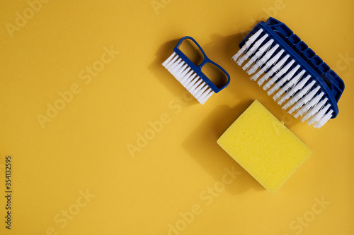 Blue dish brushes and sponge on a yellow background. Space for text