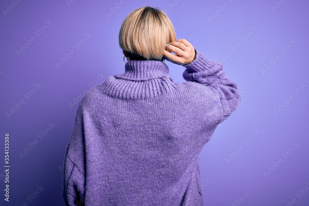 Young blonde woman with short hair wearing winter turtleneck sweater over purple background Backwards thinking about doubt with hand on head Young blonde woman with short hair wearing winter turtleneck sweater over purple background Backwards thinking about doubt with hand on head
