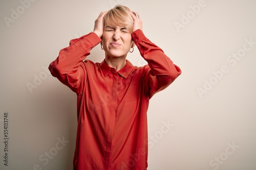 Young beautiful business blonde woman with short hair standing over isolated background suffering from headache desperate and stressed because pain and migraine. Hands on head.