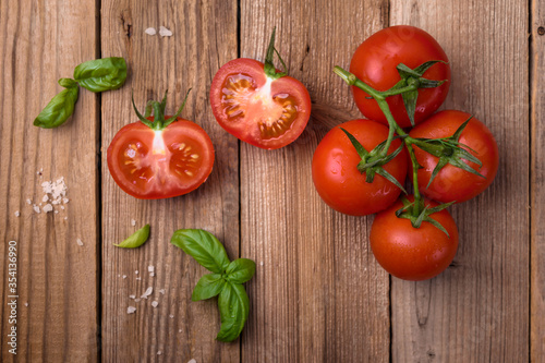 Fresh tomatoes with basil on wooden background. Copy space  top view.