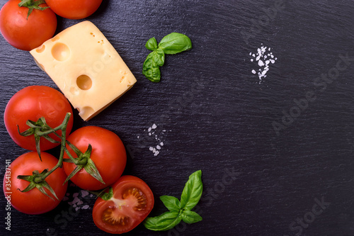  tomatoes,  cheese and basil  on black board. Italian food ingredients.