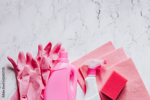 Cleaning and disinfection products agent, sponges, napkins and rubber gloves in pink colors on marble background top view copy space.