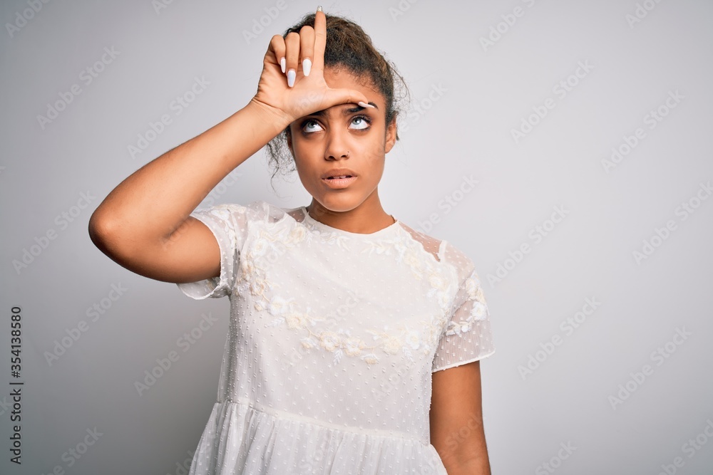 Young beautiful african american girl wearing casual t-shirt standing over white background making fun of people with fingers on forehead doing loser gesture mocking and insulting. Young beautiful african american girl wearing casual t-shirt standing over white background making fun of people with fingers on forehead doing loser gesture mocking and insulting.