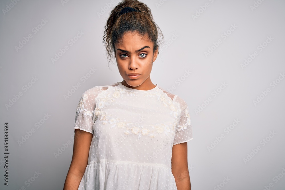 Young beautiful african american girl wearing casual t-shirt standing over white background skeptic and nervous, frowning upset because of problem. Negative person. Young beautiful african american girl wearing casual t-shirt standing over white background skeptic and nervous, frowning upset because of problem. Negative person.