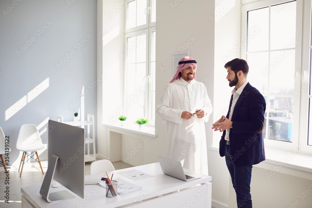 Arab and European business people are standing together in a modern office.