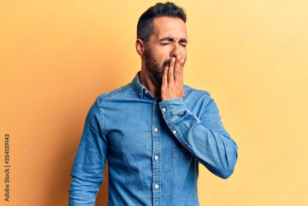 Young hispanic man wearing casual clothes bored yawning tired covering mouth with hand. restless and sleepiness.