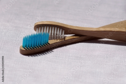Close up of the Eco-friendly white and blue bamboo toothbrushes on a white linen background. Natural organic bathroom beauty product concept. copy space