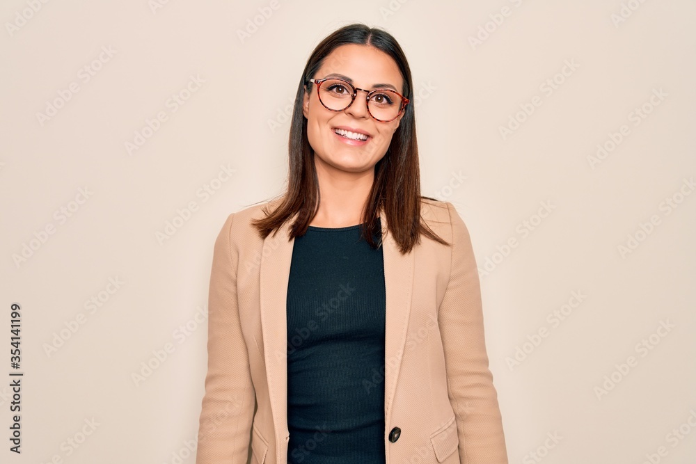 Young beautiful brunette businesswoman wearing jacket and glasses over white background with a happy and cool smile on face. Lucky person.