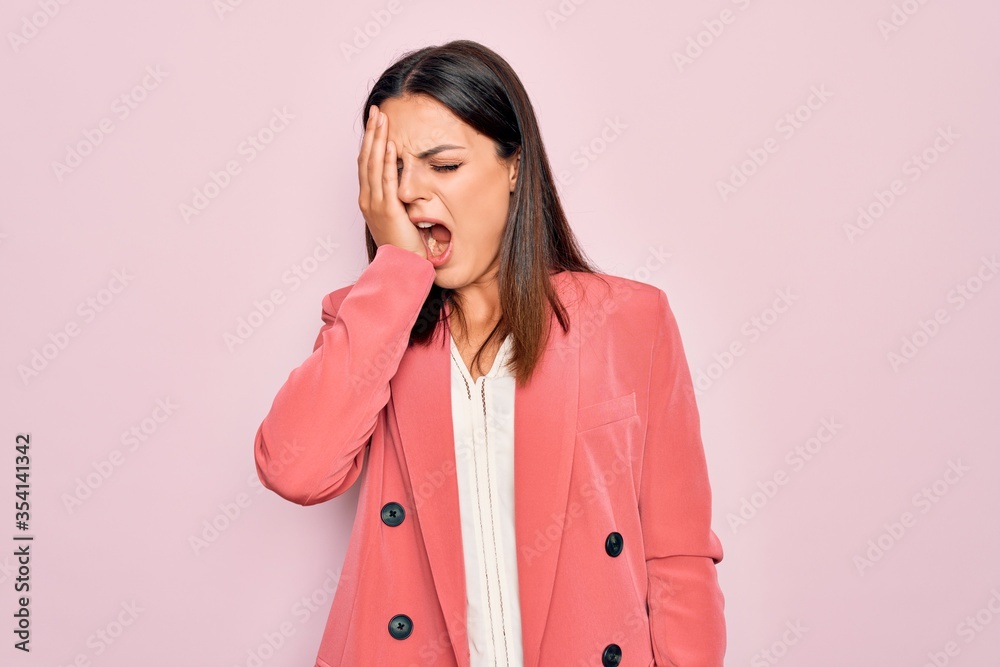 Young beautiful brunette businesswoman wearing elegant jacket over isolated pink background Yawning tired covering half face, eye and mouth with hand. Face hurts in pain. Young beautiful brunette businesswoman wearing elegant jacket over isolated pink background Yawning tired covering half face, eye and mouth with hand. Face hurts in pain.