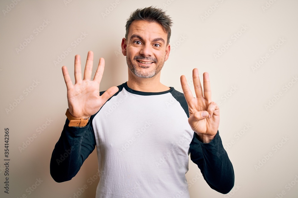 Young handsome man wearing casual t-shirt standing over isolated white background showing and pointing up with fingers number eight while smiling confident and happy. Young handsome man wearing casual t-shirt standing over isolated white background showing and pointing up with fingers number eight while smiling confident and happy.