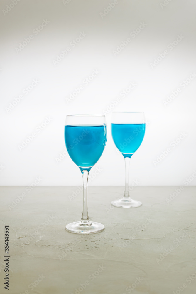 Obraz premium Two glasses of blue glitter drink on a light background. Sparkling blue wine.