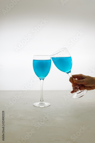 Glasses of blue glitter drink on a light background. Sparkling blue wine.