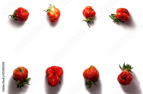 Trendy ugly food fresh red strawberry on white isolated background with hard shadows.  Misshapen produce, food waste problem concept