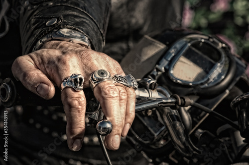 Murais de parede A biker's hand, wearing several rings, rests on the handlebar of his motorcycle,