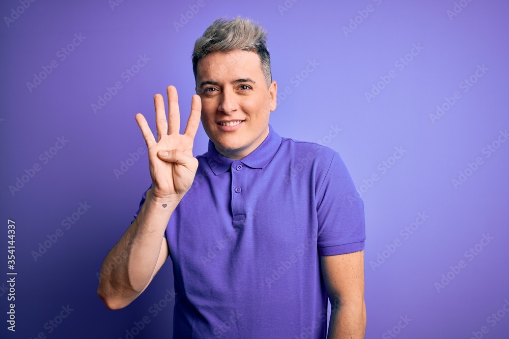 Young handsome modern man wearing casual purple t-shirt over isolated background showing and pointing up with fingers number four while smiling confident and happy.