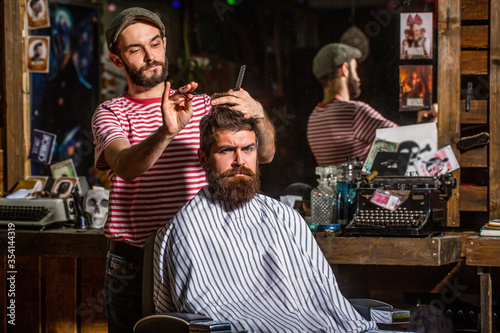 Man hairstylist. Beard man in barbershop. Hairstylist serving client at barber shop, bearded. Hairdresser, hair salon. Bearded man. Barber scissors, barber shop. Vintage barbershop, shaving