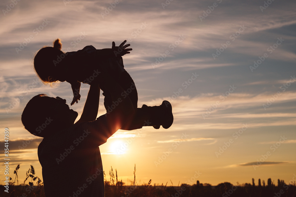 Father and son playing in the park at the sunset time.