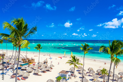 Aerial drone view of beautiful atlantic tropical beach with palms  straw umbrellas and boats. Bavaro  Punta Cana  Dominican Republic. Vacation background.