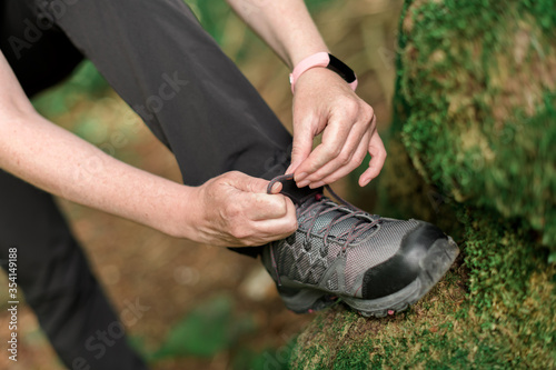 Female hiker tying shoelaces in forest