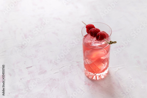 Pink rose iced cocktail with raspberry in crystal glass on table