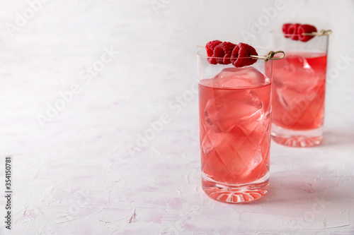 Pink rose cocktails with raspberry in crystal glass on table