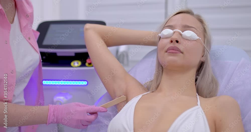 Beautician applies laser hair removal gel on armpits. Young woman makes laser hair removal procedure in a modern beauty salon, spa procedure. Beautician applies laser hair removal gel on armpits. Young woman makes laser hair removal procedure in a modern beauty salon, spa procedure.