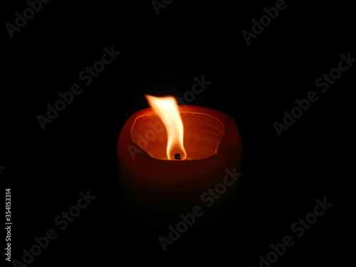 an orange lighted candle in the dark. Candle flame.