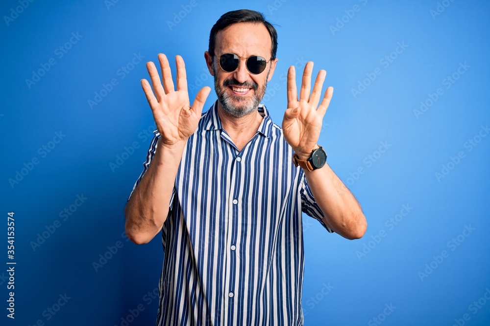 Naklejka premium Middle age hoary man wearing striped shirt and sunglasses over isolated blue background showing and pointing up with fingers number nine while smiling confident and happy.