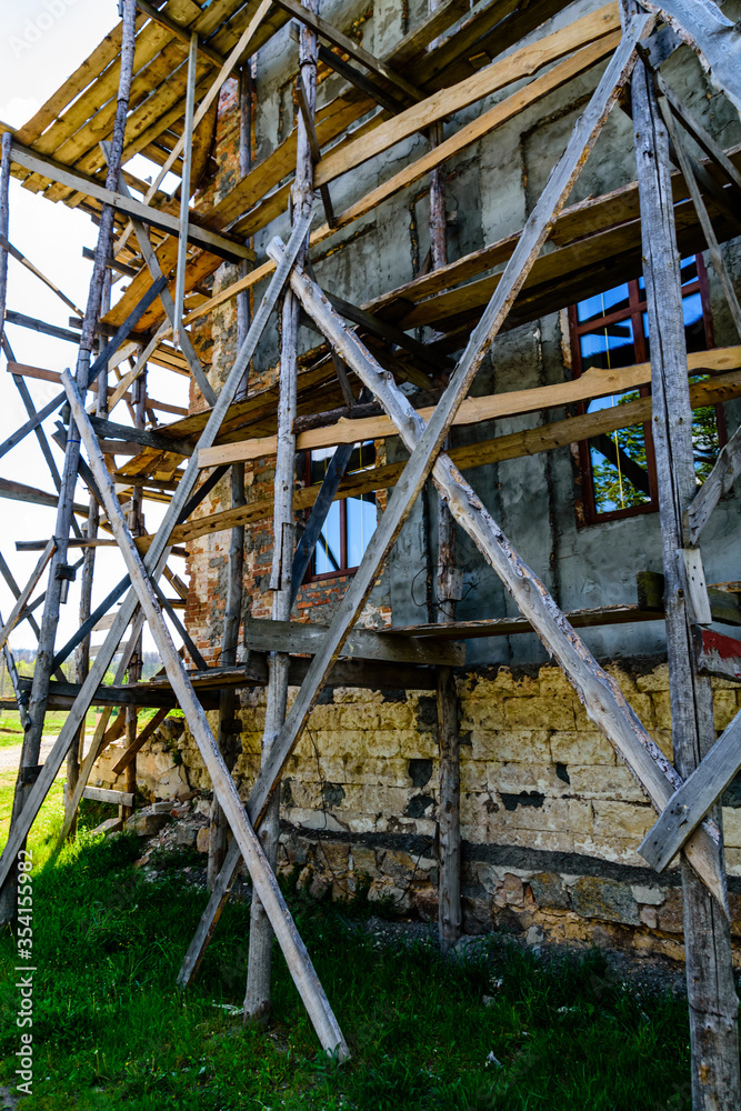 Wooden scaffolding near the old building. Ancient building restoration Wooden scaffolding near the old building. Ancient building restoration