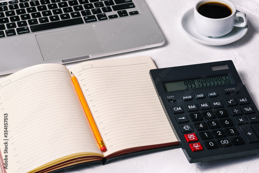 Calculator, a diary, an open laptop, a Cup of coffee, and a notebook on the desktop. Accounting, Finance and business Calculator, a diary, an open laptop, a Cup of coffee, and a notebook on the desktop. Accounting, Finance and business