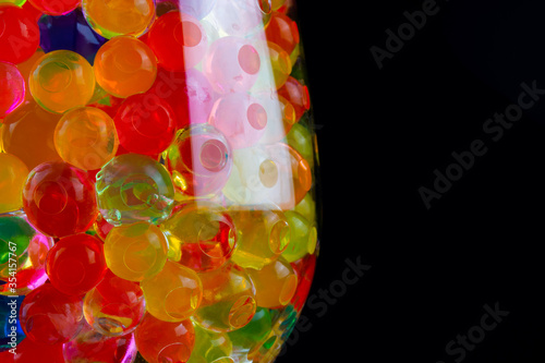 multi-colored silicone gel balls in a glass on a black background photo