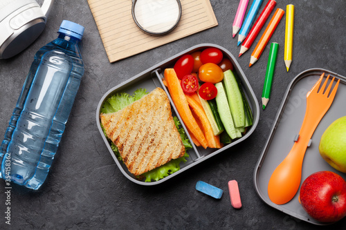 School lunch box and education stationery on stone table