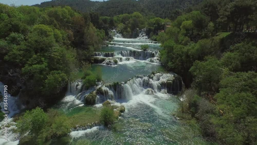 Aerial shot of idyllic waterfall in forest against sky, drone is flying backward over river - Krka, Croatia Aerial shot of idyllic waterfall in forest against sky, drone is flying backward over river - Krka, Croatia