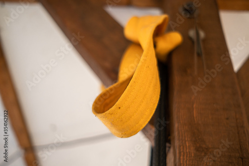 Low angle view of yellow karate belt knotted to wooden beam