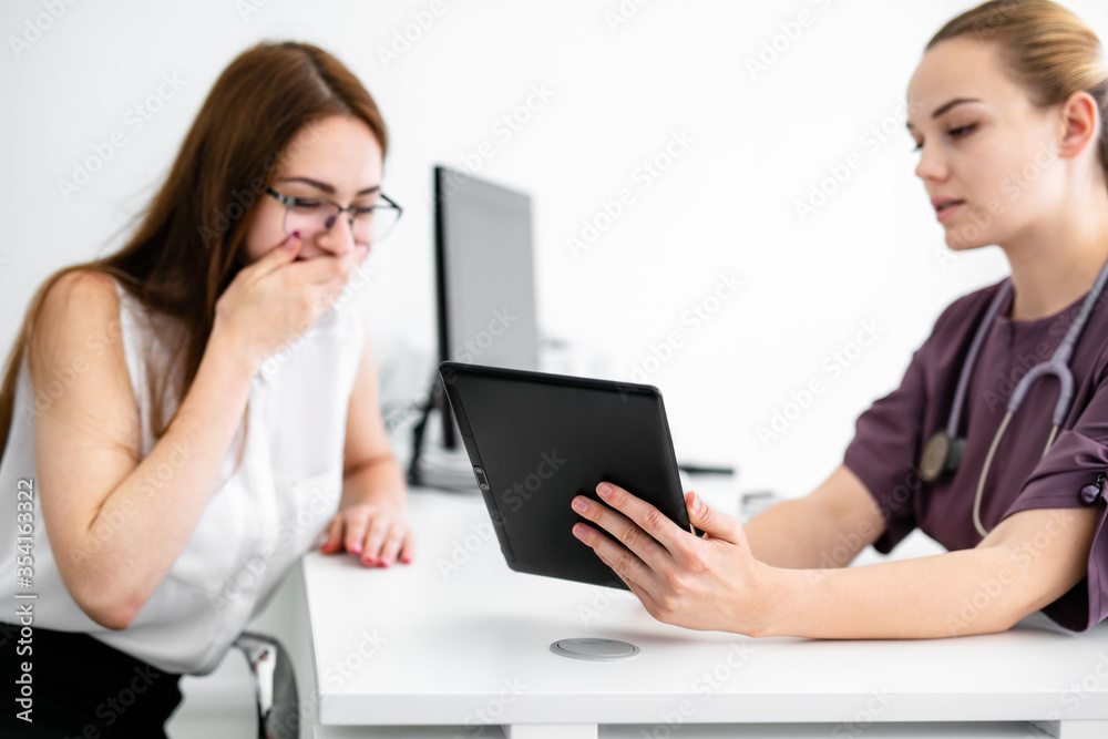 Close up of female doctor and patient sitting at the desk in modern clinic. Close up of female doctor and patient sitting at the desk in modern clinic.