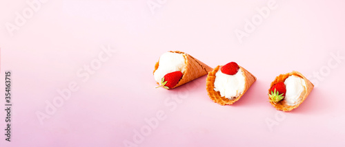 Ice cream in waffle cones with fresh strawberries on pink background. National ice cream day 19 july or hello summer concept. Close-up