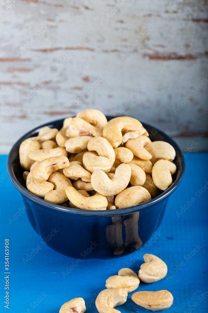 Cashew in a ceramic bowl on a white wooden background. Cashew in a ceramic bowl on a white wooden background.