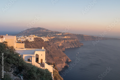 View of the cliffs and traditional Aegean structures of Santorini under the sunset's light