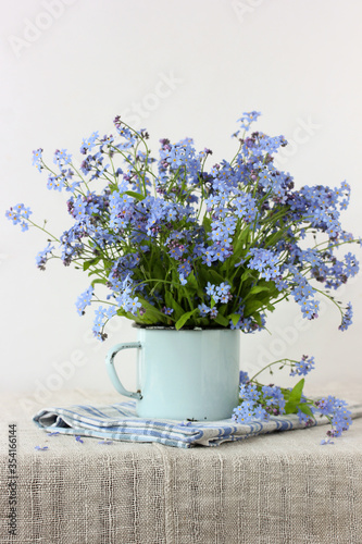 blue forget-me-nots in an enameled mug.