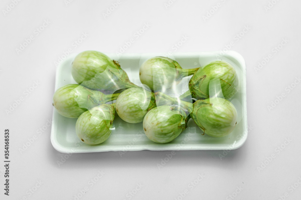 Green eggplant photos in packed in a white foam tray with a white background