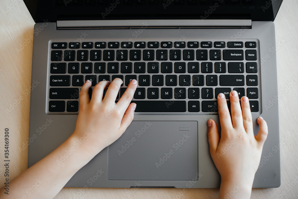 Hands of a child close-up on the laptop keyboard. Distance learning. Stay at home Hands of a child close-up on the laptop keyboard. Distance learning. Stay at home