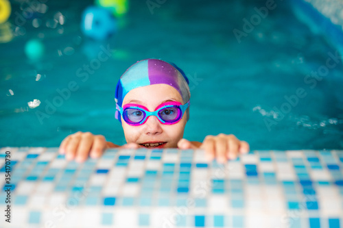 Konstfotografi Happy girl in pink swimsuit with swimming hat and glasses in the blue pool in sp