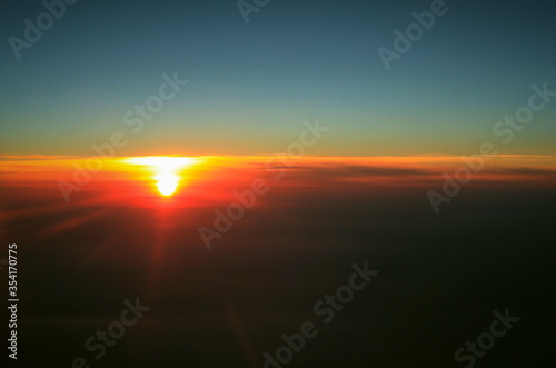 bright red sun in a high sky view from the plane window