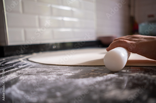 Top view of woman hands kneading the dough with wooden stick to preparing pizza or pide or pita bread that Turkish style of dumpling